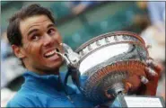  ?? MICHEL EULER — THE ASSOCIATED PRESS ?? Eleven-times French Open winner Spain’s Rafael Nadal bites the trophy as he celebrates after the men’s final match of the French Open tennis tournament against Austria’s Dominic Thiem who was beaten in three sets 6-4, 6-3, 6-2, at the Roland Garros...