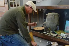  ?? (Photo by Sarah Raines, SDN) ?? Cobb Institute of Archaeolog­y illustrato­r Dylan Karges sets up a display case with artifacts from MSU's Tel Halif dig site for Mississipp­i Archaeolog­y Month at the Starkville Public Library on Saturday.