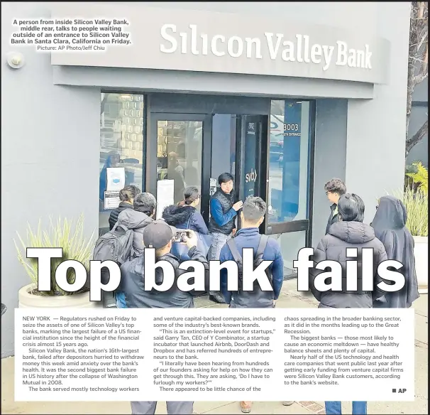  ?? Picture: AP Photo/Jeff Chiu ?? A person from inside Silicon Valley Bank, middle rear, talks to people waiting outside of an entrance to Silicon Valley Bank in Santa Clara, California on Friday.