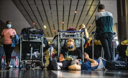  ?? JEROME DELAY/ASSOCIATED PRESS ?? Norwegian students who had been on a field trip to South Africa wait to be tested for COVID-19 before boarding a flight home on Monday. The World Health Organizati­on has urged countries not to impose flight bans on African nations over virus concerns.