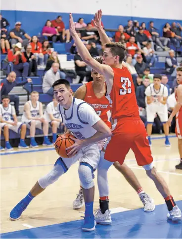  ?? GABRIELA CAMPOS/THE NEW MEXICAN ?? St. Michael’s Thomas Wood eyes the basket while being guarded by Robertson’s defenders Friday at Perez-Shelley Gymnasium. St. Michael’s beat Robertson, 75-48.