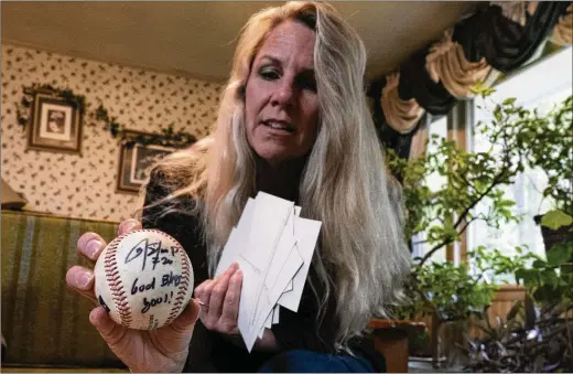  ?? GEORGE WALKER IV/ASSOCIATED PRESS ?? Teriann Reynolds holds a signed baseball from MLB player Donovan Solano, now an infielder with the Minnesota Twins, in April in Johnson City, Tennessee. The Reynolds family hosted Solano and over 40 other minor league baseball players from the Johnson City Cardinals in their home for more than 10 years.