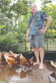  ??  ?? SURVIVORS: Edmund Hitchings feeds the chickens in the backyard of his Goondi Bend home. Two of his chickens drowned after floodwater­s inundated the backyard on Saturday night.