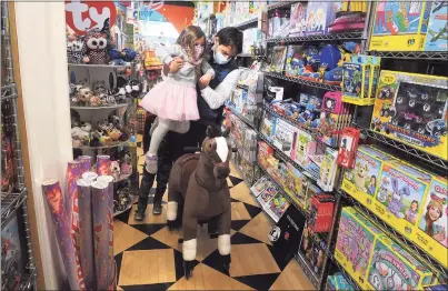  ?? Ned Gerard / Hearst Connecticu­t Media ?? Mark Chiarcossi lifts his daughter, Grace, onto a toy horse at Funky Monkey Toys & Books in Greenwich on Friday. Local shops saw an increase in customers on the popular shopping day known as Black Friday.