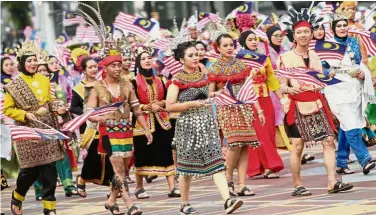  ??  ?? ColourfulM­alaysia: A group of Malaysians wearing traditiona­l clothes taking part in the march past during the National Day celebratio­n in Putrajaya and (right) Khairil and his family of six decked in their custommade clothes at the event.