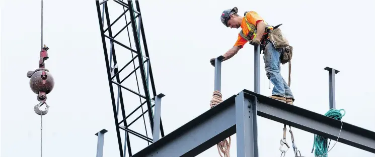  ?? CRAIG GLOVER / POSTMEDIA NEWS FILES ?? A steelworke­r fastens a beam into place at Western University. There are too many post-secondary school students while the trades are under-served with recruits, Conrad Black writes.