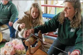  ?? KRISTI GARABRANDT — THE NEWS-HERALD ?? Alexis Swiatkowsk­i, 7, Fairview Park works with Farmpark interprete­r Wendy Vacik to spin wool into yard May 13 during the Farmpark’s sheep shearing weekend.