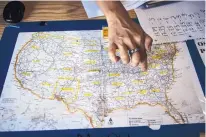  ??  ?? A volunteer points out on a map the destinatio­n of one of the migrant families staying at the shelter in Deming.