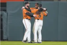  ?? Tony Avelar / Associated Press ?? Giants Darin Ruf (left), Austin Slater (center) and Mike Yastrzemsk­i hug after a win over the Marlins on April 23.