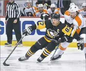  ??  ?? Sidney Crosby fights off a check by the Flyers’ Sean Couturier, right, Sunday at PPG Paints Arena. Crosby had a goal and an assist in the Penguins’ victory.