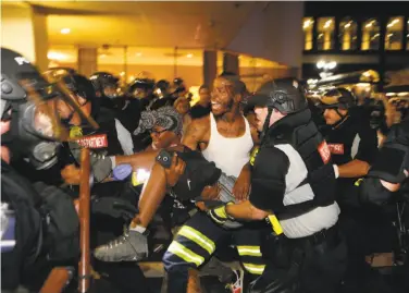  ?? Brian Blanco / Getty Images ?? Police and protesters carry a seriously wounded demonstrat­or into the parking area of the the Omni Hotel during a march over the Tuesday afternoon shooting death by police of a black man.