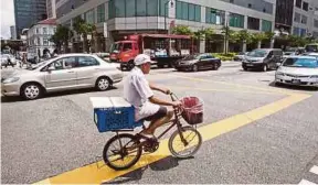  ?? BLOOMBERG PIC ?? An old man cycling past traffic at the Chinatown area of Singapore. A new study from Oxford Economics shows Singapore’s labour supply will shrink by 1.7 percentage points in the 10 years through 2026 and by 2.5 percentage points in the decade after that.