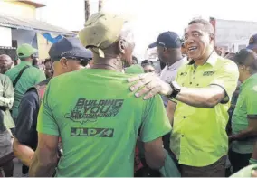  ?? ?? Prime Minister Andrew Holness (right) greets a Jamaica Labour Party supporter on the hustings last week.