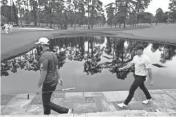  ?? PHOTOS BY ROB SCHUMACHER/THE REPUBLIC ?? Above: Dustin Johnson, left, and Rory McIlroy cross Sarazen Bridge as they play the 15th hole during a practice round ahead of the Masters at Augusta National Golf Club on Tuesday. Below: Bryson DeChambeau, right, talks with caddie Tim Tucker at the ninth hole during a practice round for the Masters on Tuesday.