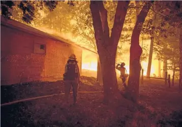  ?? CHRISTIAN MONTERROSA/THE NEW YORK TIMES PHOTOS ?? A crew wets down a building while battling the Dixie fire in August near Taylorsvil­le, Calif. Communitie­s in the wildfire danger zone are struggling to protect their disabled and older residents.