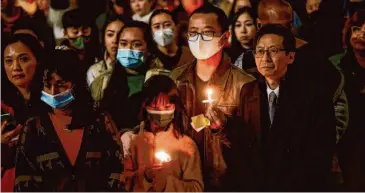  ?? Gabrielle Lurie/The Chronicle ?? Leto Sze, 9, and father Michael Sze hold candles last month as they listen during the AAPI Unite candleligh­t vigil honoring the victims of the Monterey Park, Half Moon Bay and East Oakland shootings in Oakland.