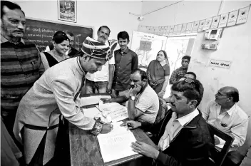  ??  ?? A groom signs a register before casting his vote at a polling booth during the first phase of state assembly election in Limbdi town of Surendrana­gar district in Gujarat. Indian Prime Minister Narendra Modi’s home state of Gujarat went to the polls on...