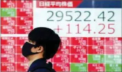  ?? Eugene Hoshiko/ap ?? a man wearing a protective mask walks past an electronic stock board showing Japan’s nikkei 225 index at a securities firm in Tokyo, Japan, on March 3, 2021.