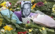  ?? Frank Augstein/Associated Press ?? A photo of Britain’s Prince Philip is among flowers left by the public Saturday outside the gates of Windsor Castle in Windsor, England. Philip, Queen Elizabeth’s husband of more than seven decades, died Friday.
