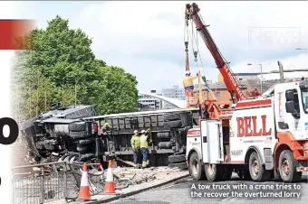  ?? ?? A tow truck with a crane tries to the recover the overturned lorry