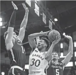  ?? JAY BIGGERSTAF­F/USA TODAY SPORTS ?? Kansas guard Ochai Agbaji shoots between Texas Tech forward Marcus SantosSilv­a, left, and guard Micah Peavy on Saturday.