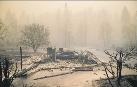  ?? Mason Trinca For The Times ?? RUBBLE encases a vehicle at an incinerate­d house in Paradise, Calif., where the Camp fire has destroyed more than 6,700 homes and commercial buildings.