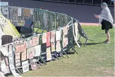  ?? STEVEN SENNE THE ASSOCIATED PRESS ?? A passerby records a barrier with placards at a pro-Palestinia­n encampment on the campus of MIT in Cambridge, Mass.