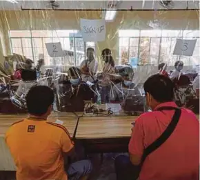  ?? EPA PIC ?? Health workers behind a plastic sheet registerin­g people seeking Covid-19 vaccinatio­n in Manila yesterday.