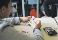  ??  ?? A student looks at his stickers, which can give lessons in language skills as well as geography and history.