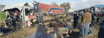  ?? — AFP ?? Security officers gather at the site of a collision, after a train slammed into a public bus and tore it in two, in the area of Jebel Jalloud, near Sidi Fathallah, on Wednesday.