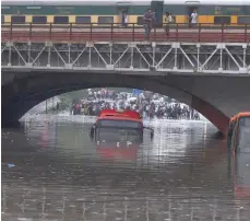  ?? — Reuters ?? Buses are seen submerged on a flooded road under a railway bridge after heavy rains in New Delhi.