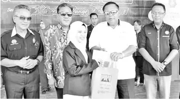  ??  ?? Sairin presenting a prize to a winner of the inter-secondary school speech competitio­n. Looking on are Sazali (right) and others.