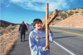  ?? EDDIE MOORE/JOURNAL ?? Fil Matthew, 11, and his family, from Rio Rancho, carry a wooden cross along Santa Fe County Road 98 on their way the Santuario de Chimayo on Good Friday last year.