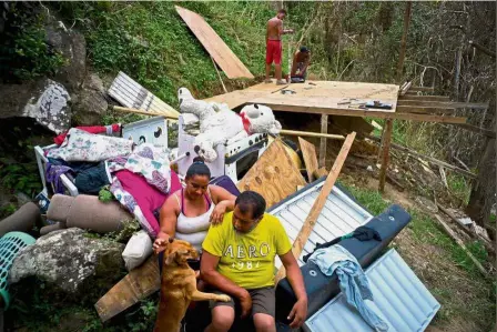  ??  ?? Very little left: A couple considerin­g their next option while their children build a shelter to protect themselves from the elements in Moravis, Puerto Rico. — AP