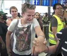  ?? Vincent Thian/ Associated Press ?? Travelers react as they make their way through the protesters to the departure gates during a demonstrat­ion Tuesday at the Hong Kong Internatio­nal Airport. Protesters crippled operations at the airport for a second day. Authoritie­s canceled all remaining flights out of the city after demonstrat­ors took over the terminals as part of their push for democratic reforms.