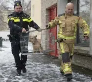  ?? JASPER JUINEN/THE NEW YORK TIMES ?? Sgt. Erik Smit, left, and a firefighte­r rescue a dog that had been left alone on a balcony during a snowfall.