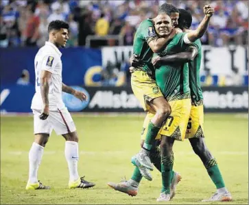  ?? David Goldman
Associated Press ?? DeANDRE YEDLIN of the United States walks off the pitch as Jamaica players, from left, Joel McAnuff, Rudolph Austin and Je-Vaughn Watson celebrate their 2-1 victory over the Americans.