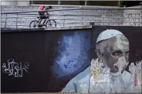  ?? NATACHA PISARENKO — THE ASSOCIATED PRESS FILE ?? A cyclists pedals his bike up a ramp near a weathered mural of Pope Francis, in Buenos Aires, Argentina, Thursday, March 2, 2023. Francis left Argentina in February 2013to attend the conclave that elected him as the successor to Benedict XVI on March 13.