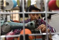  ??  ?? Taiwanese “qipao” maker Lee Wei-fan sewing at his studio in Taipei.