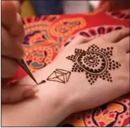  ?? (AP/Chiang Ying-ying) ?? An artist applies henna on the hand of a woman Thursday during the Hindu festival of lights, Diwali, in Taipei, Taiwan.