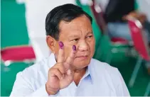  ?? ?? Με το μελάνι από τη διαδικασία στα δάχτυλα, ο Πραμπόβο Σουμπιάντο κάνει το σήμα της νίκης στο εκλογικό τμήμα όπου ψήφισε. Πολλοί λένε ότι τα χέρια του είναι βαμμένα και με αίμα – από τη σφαγή στο Ανατολικό Τιμόρ κ.λπ.
