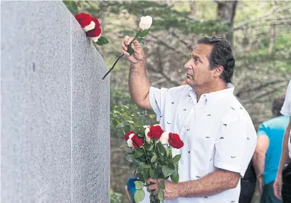  ?? ANDREW VAUGHAN THE CANADIAN PRESS ?? Stephen Thompson from Atlanta, Ga., places roses in remembranc­e of his father, who died in the crash of Swissair Flight 111.