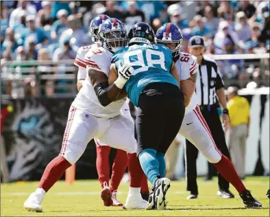  ?? Phelan M. Ebenhack / Associated Press ?? New York Giants offensive tackle Evan Neal, left, blocks against Jacksonvil­le Jaguars defensive tackle Corey Peters during the first half on Oct. 23 in Jacksonvil­le, Fla.