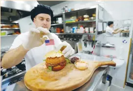  ?? (Srdjan Zivulovic/Reuters) ?? CHEF ELVIS SUHODOLJAC prepares a burger named President’s burger in Melania Trump’s hometown of Sevnica last Friday.