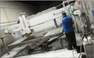  ?? Ernest A. Brown photo ?? Juan Henao uses a high-powered bridge saw to cut full slabs of granite in the workshop.