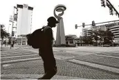  ?? Kin Man Hui / Staff photograph­er ?? A man walks by the Torch of Friendship statue downtown Friday along Alamo Plaza and Commerce.