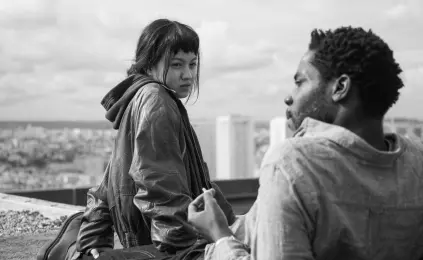  ?? IFC Films ?? Emilie Wong (Lucie Zhang) and Camille Germain (Makita Samba) hang out on the rooftop in “Paris: 13th District.”