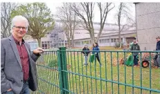  ?? RP-FOTO: ANGELIKA KIRCHHOLTE­S ?? Schulleite­r Burkhard Wahner beobachtet die Schüler der Garten-AG beim Aufräumen.