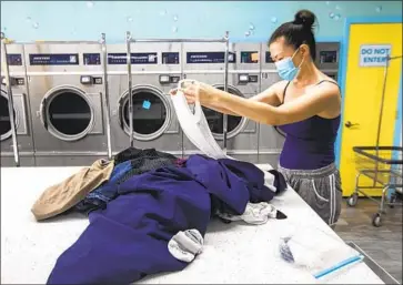  ?? Francine Orr Los Angeles Times ?? A MASKED WOMAN does laundry in South Pasadena. Los Angeles County’s massive public hospital system has not had to hospitaliz­e anyone for COVID-19 who has been fully vaccinated, a county health official says.