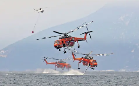 ??  ?? Firefighte­rs fill helicopter­s with water from the sea near the village of Pefki on the Greek island of Evia ready to dump it on dozens of wildfires which have raged for nine days